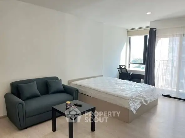 Spacious modern bedroom with natural light and cozy seating area.