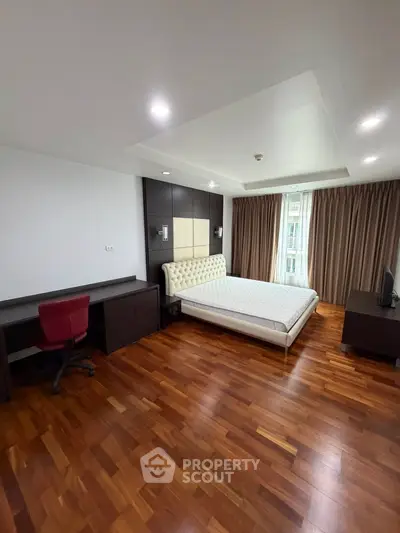 Spacious bedroom with wooden flooring and modern furnishings in a luxurious apartment.
