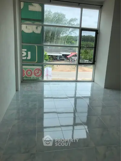 Spacious room with large window offering natural light and street view, ideal for versatile use.