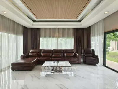Luxurious living room with leather sofa and marble flooring, featuring large windows and elegant ceiling design.
