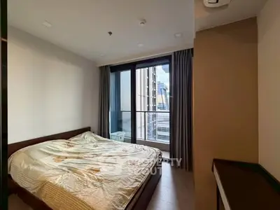 Cozy bedroom with large window and city view, perfect for urban living.