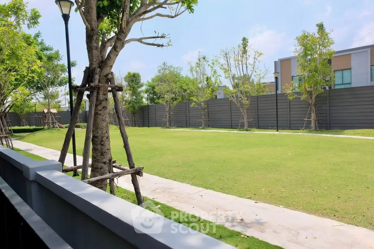 Spacious garden view with lush greenery and modern fence in a serene residential area.