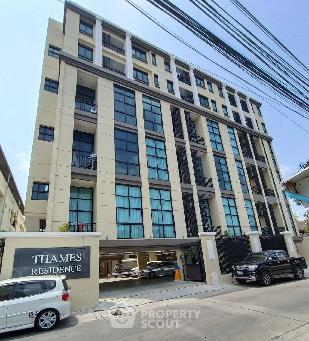 Modern multi-story residential building with parking and sleek facade.