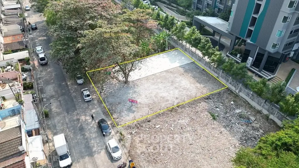 Prime vacant land plot in urban area with potential for development, surrounded by greenery and modern buildings.