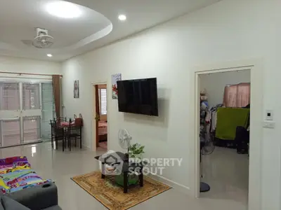 Spacious living room with modern decor and wall-mounted TV, featuring a cozy seating area and dining space.