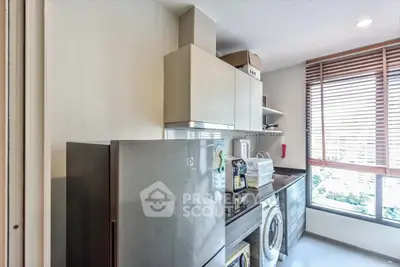 Modern kitchen with sleek appliances and large window offering natural light