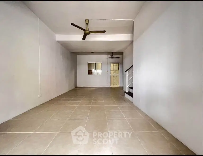 Spacious interior with tiled flooring and ceiling fans, ideal for customization.