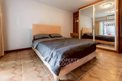 Spacious bedroom with mirrored closet and elegant tile flooring