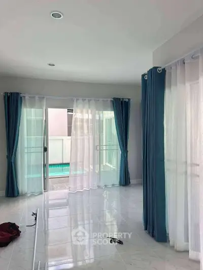 Spacious living room with pool view and elegant blue curtains
