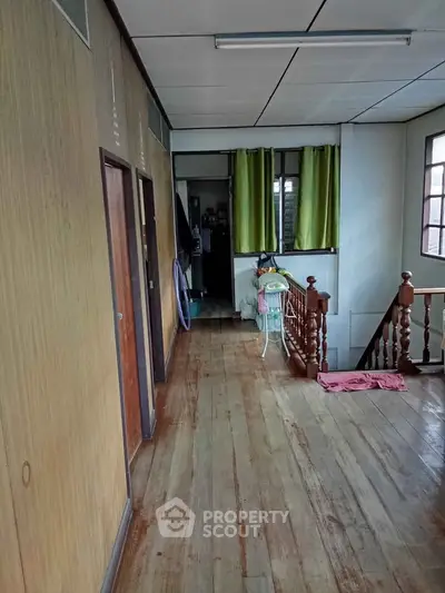 Charming vintage hallway with wooden floors and railing, featuring natural light from windows and cozy decor.