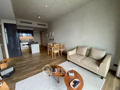 Modern living room with open kitchen, stylish furniture, and wooden flooring in a cozy apartment.