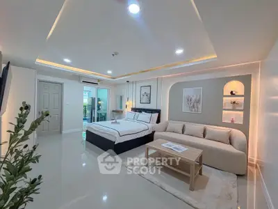 Spacious modern bedroom with elegant decor and cozy seating area