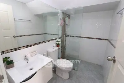Modern bathroom with glass shower, sleek sink, and contemporary design.