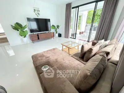 Spacious modern living room with large sofa and flat-screen TV, perfect for relaxation.