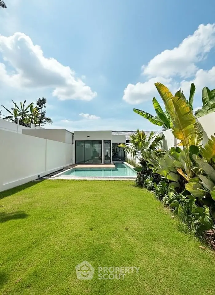 Luxurious modern home with private pool and lush garden under a clear blue sky.