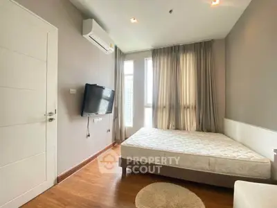 Modern bedroom with natural light, featuring a wall-mounted TV and air conditioning.