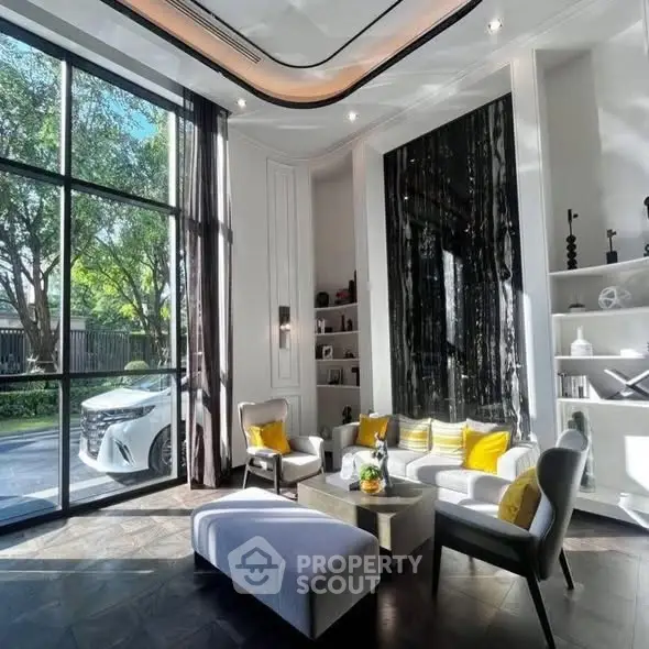 Luxurious living room with high ceilings, large windows, and elegant decor overlooking a garden view.