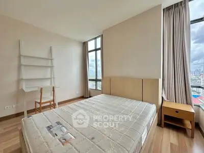 Spacious bedroom with large windows offering stunning city views, featuring a minimalist design and ample natural light.
