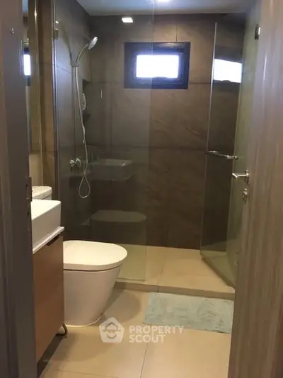 Modern bathroom with glass shower and sleek fixtures in contemporary apartment.