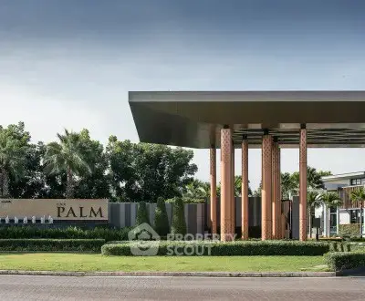 Luxurious modern building entrance with sleek design and lush greenery.