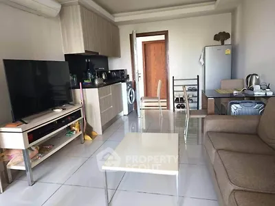 Modern living room with open kitchen, featuring sleek appliances and cozy seating area.