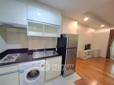 Modern kitchen with sleek appliances and cozy living area in open layout apartment.