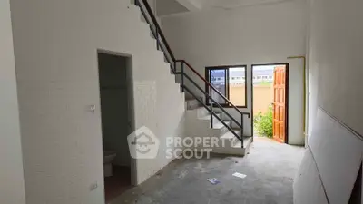 Spacious interior with staircase and open door leading to outdoor area, ideal for renovation.