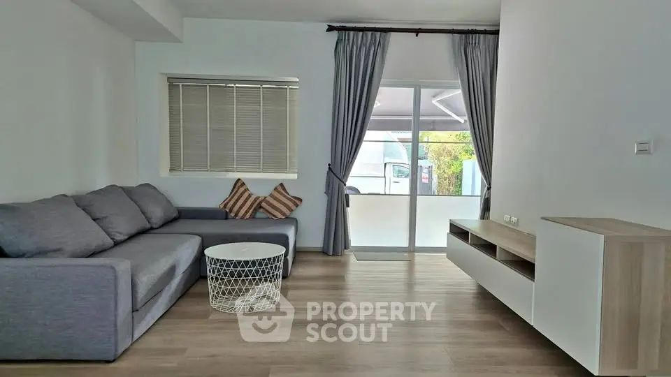 Modern living room with gray sofa, stylish coffee table, and balcony access.