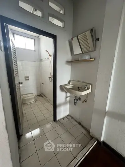 Compact bathroom with shower and sink, ideal for small apartments or guest rooms.