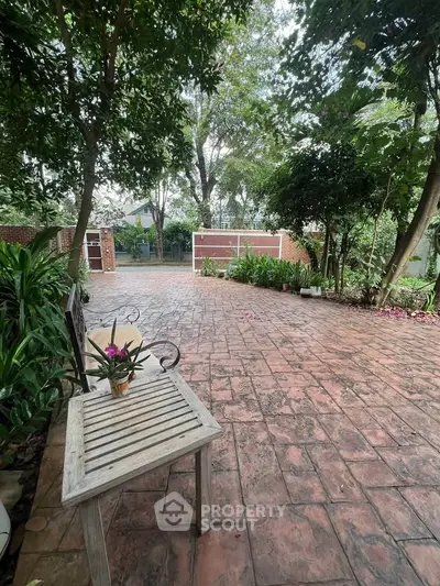 Charming garden patio with rustic bench and lush greenery, perfect for outdoor relaxation and entertaining.