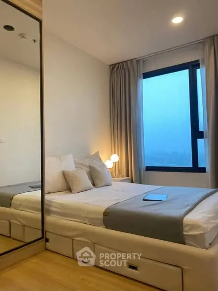 Modern bedroom with large window and mirrored closet in stylish apartment.