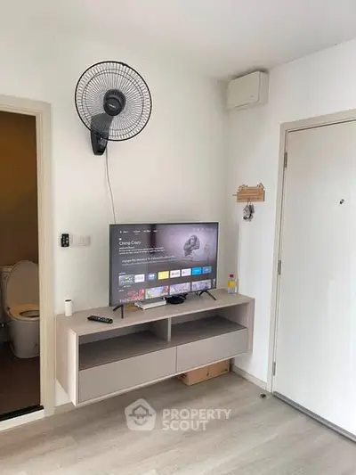 Modern living room with wall-mounted TV and fan, showcasing minimalist design and sleek flooring.