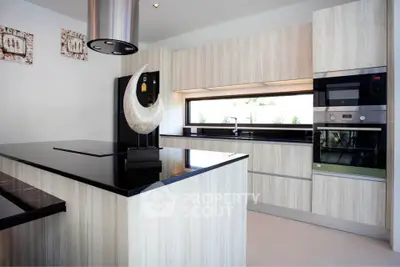Modern kitchen with sleek black countertops and built-in appliances in a stylish home.