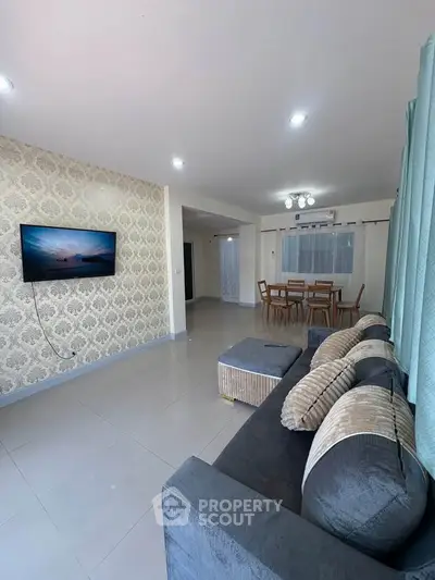 Spacious living room with modern decor and wall-mounted TV in a stylish apartment.