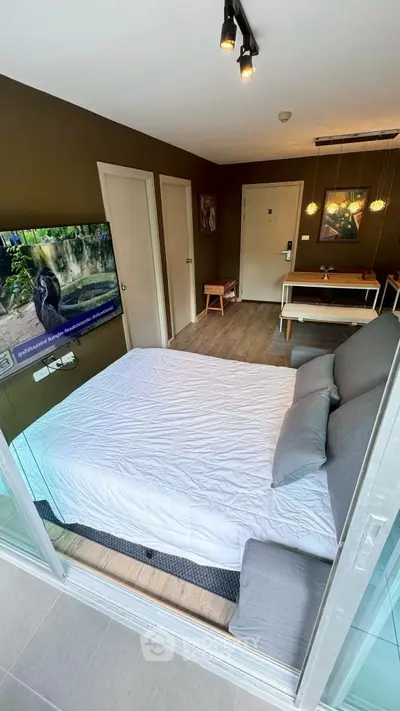 Modern studio apartment with cozy bed, wall-mounted TV, and stylish decor.