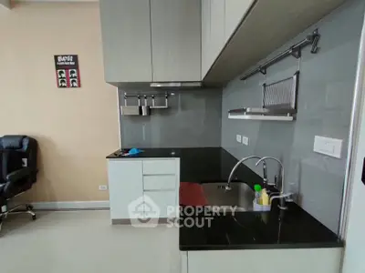 Modern kitchen with sleek cabinetry and black countertops, featuring a compact and efficient design.