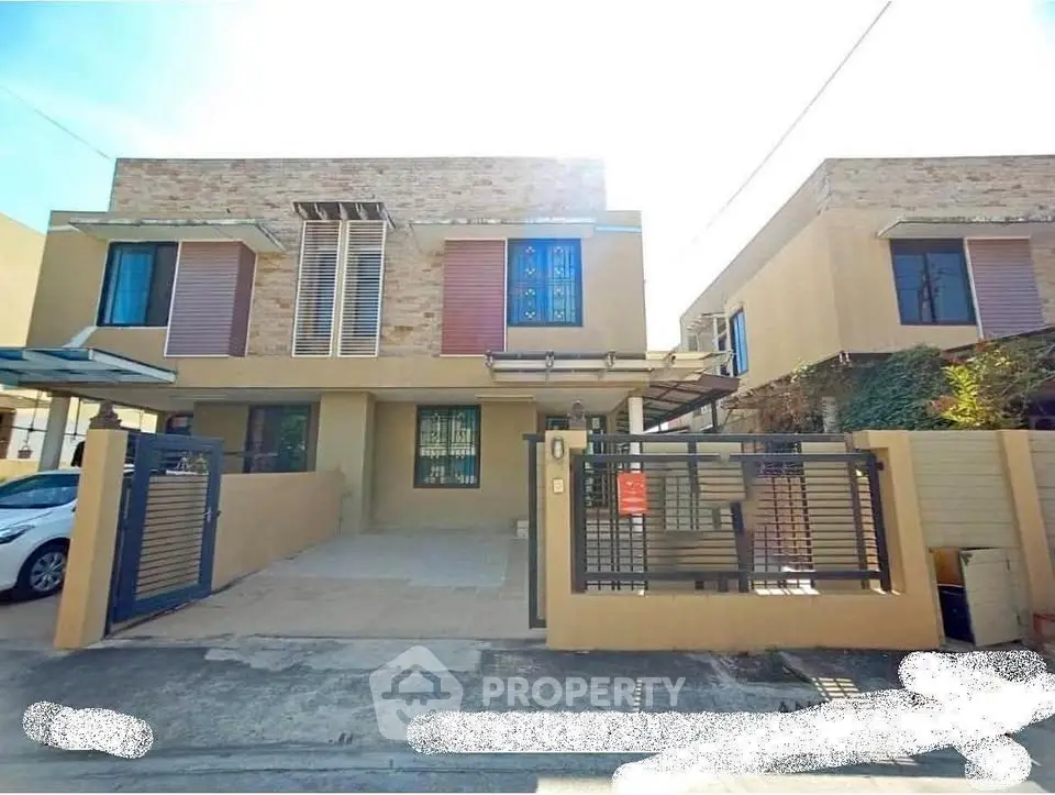 Modern two-story house with gated driveway and contemporary design.