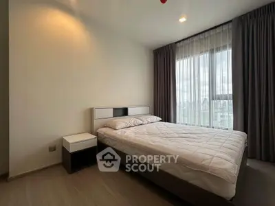 Modern bedroom with large window and elegant curtains in a stylish apartment.