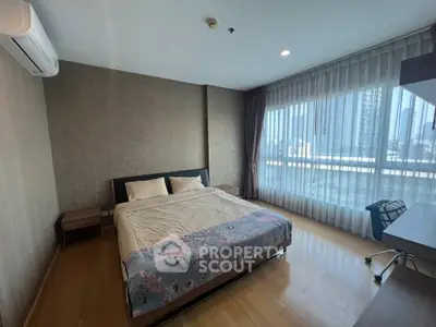 Spacious bedroom with city view, modern decor, and natural light in a high-rise apartment.