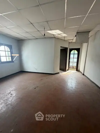 Spacious empty room with large windows and tiled ceiling, ideal for customization.