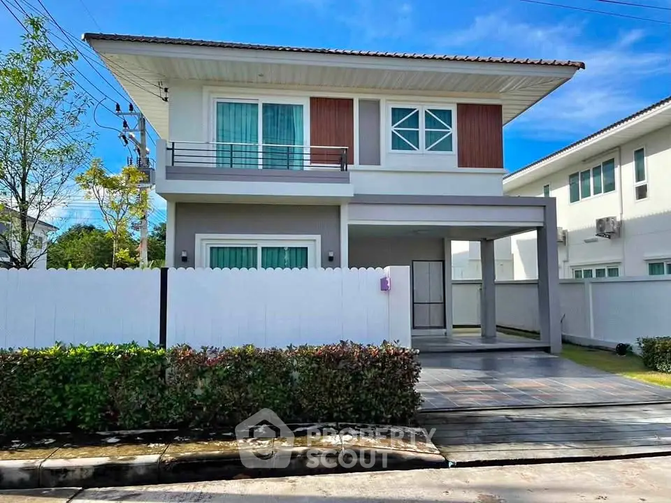 Modern two-story house with balcony and driveway in a serene neighborhood.
