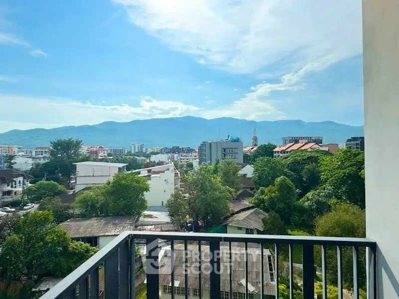 Stunning balcony view overlooking lush greenery and cityscape with mountains in the background.