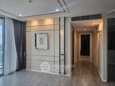 Modern apartment interior with elegant wall decor and large windows offering city views.