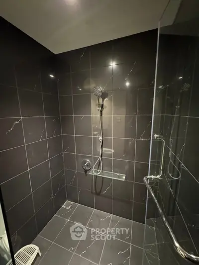 Modern bathroom with sleek black tiles and glass shower enclosure