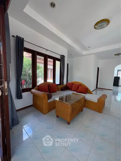Spacious living room with wicker furniture and large windows in a modern home.