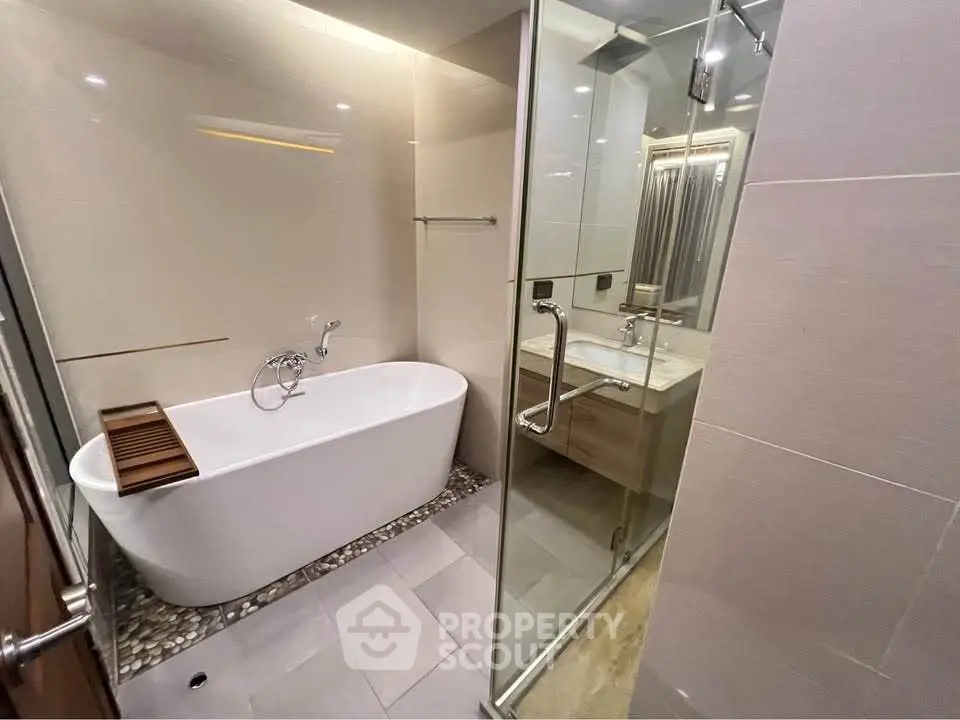 Luxurious modern bathroom with freestanding bathtub and glass shower enclosure.