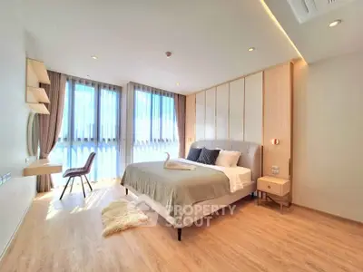Spacious and bright bedroom with modern decor and large windows in a luxury apartment.