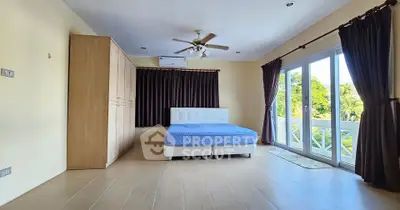 Spacious bedroom with large windows and elegant curtains, featuring a comfortable bed and ample closet space.