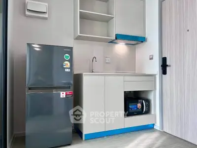 Modern compact kitchen with sleek appliances and minimalist design in a stylish apartment.
