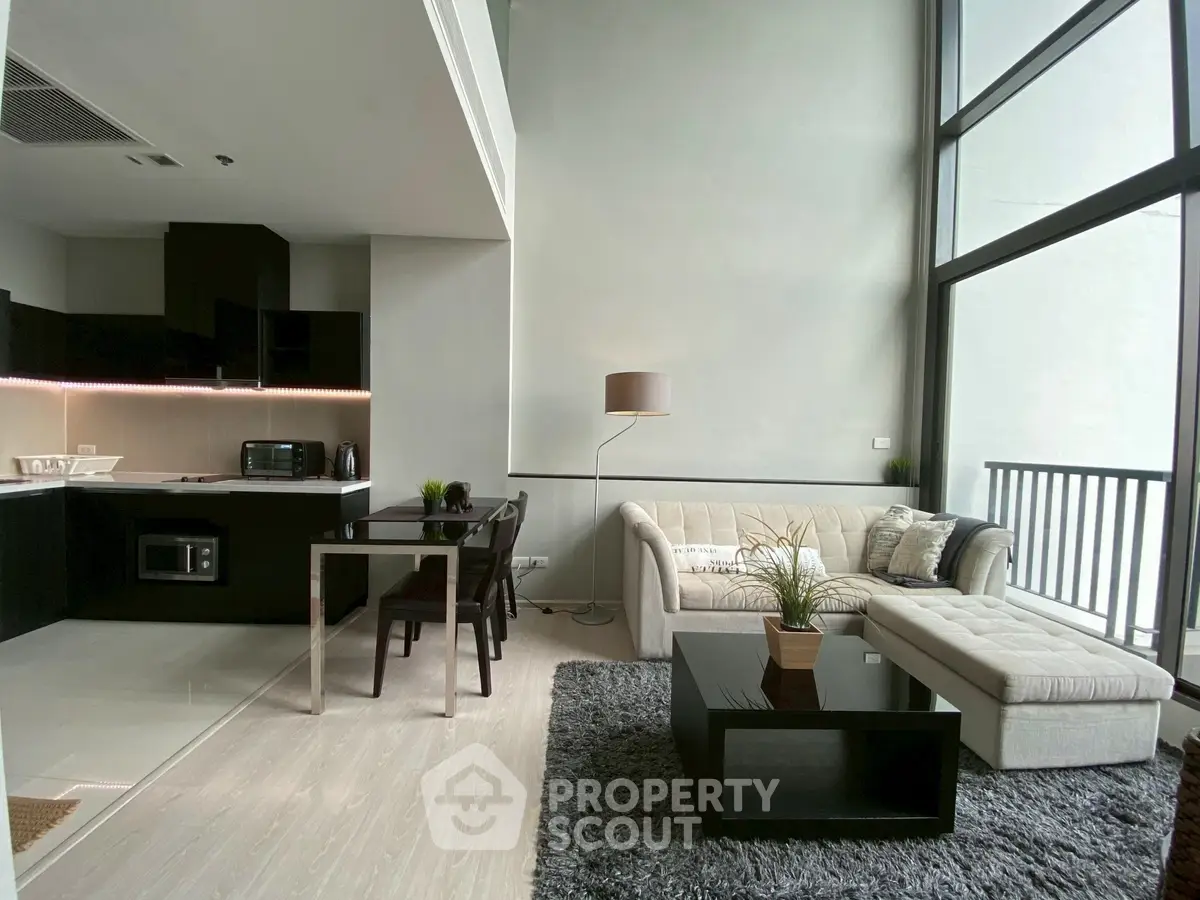 Modern living room with open kitchen and high ceiling windows